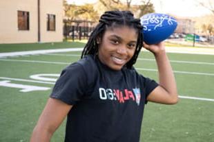 young teen female smiling while throwing a blue football